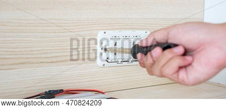 Man Hand Using Screwdriver Installing Wire Cables For Socket Plug. Renovation, Repair, Fixing And De