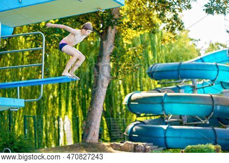 Active Teenager Boy Jumping Into An Outdoor Pool From Spring Board Or 5 Meters Diving Tower Learning