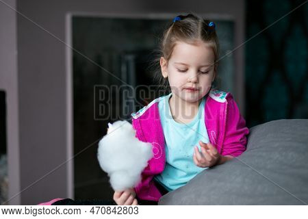 Portrait Of Little Girl With Fair Hair Holding Delicious White Cotton Candy Candyfloss, Looking At S