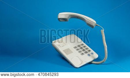 White Landline Phone On A Blue Background. Business Conversations And Cold Calls Concept