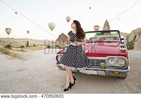 Beautiful Girl In Retro Style Posing Near A Vintage Red Cabriolet Car On Background Of Balloons In C