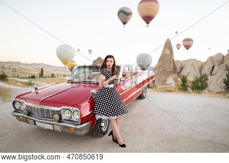Beautiful Girl In Retro Style Posing Near A Vintage Red Cabriolet Car On Background Of Balloons In C