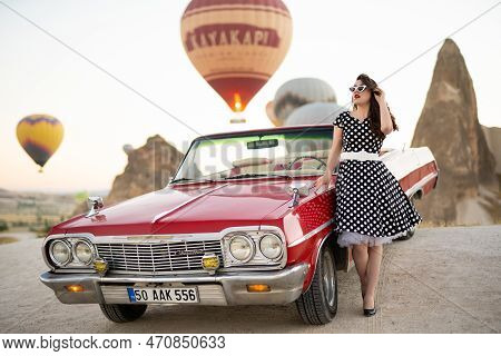 Goreme, Turkey, Cappadocia- June 30, 2021: Beautiful Girl In Retro Style Posing Near A Vintage Red C