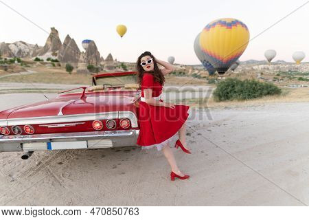 Beautiful Girl In Retro Style Posing Near A Vintage Red Cabriolet Car On Background Of Balloons In C