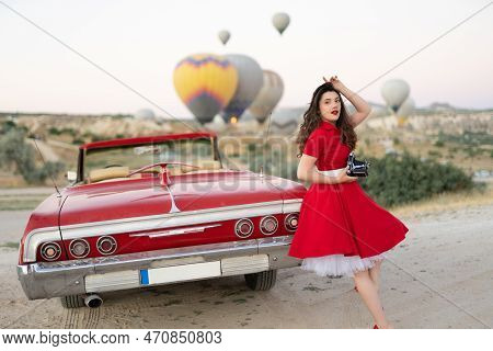Beautiful Girl Retro Style Posing Near Vintage Red Cabriolet Car With Old Film Camera  On Background