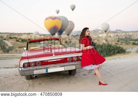 Beautiful Girl Retro Style Posing Near Vintage Red Cabriolet Car With Old Film Camera  On Background