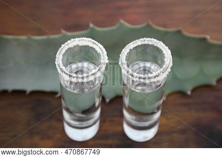 Mexican Tequila Shots With Salt And Green Leaf On Wooden Table, Closeup. Drink Made Of Agava