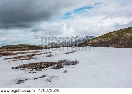 Scenic Landscape With Last Year Snow On Moss Mountain Pass And High Snowy Mountain Range In Sunlight