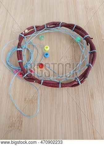 First Nations Dreamcatcher In The Process Of Being Made With Sinew And Beads On A Wood Background