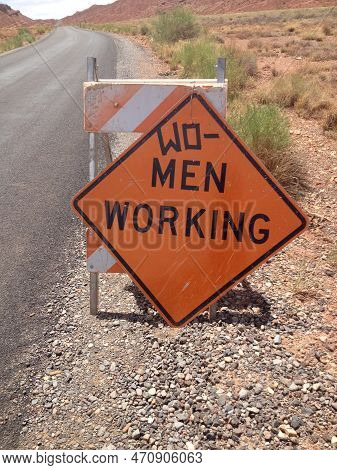 Women Working Orange Caution Sign By Road