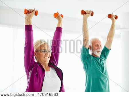 Senior Couple Exercise Stretching And Exercising With Dumbbell Lifting Weigth At Home Health Care