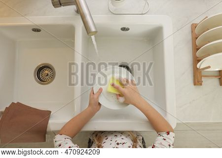 Girl Washing Plate Above Sink In Kitchen, Top View