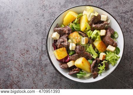 Gourmet Salad With Gizzards And Fried Potatoes Close-up In A Plate On The Table. Horizontal Top View