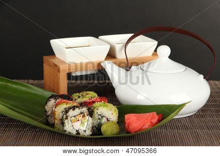 Velsmagende Maki sushi - Roll på grønne blade på bordet på grå baggrund
