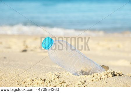 Empty Plastic Bottle From Drinking Water In Sea Waves And Sand. The Problem Of Ocean Plastic Polluti