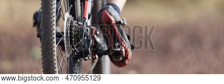 Mountain Biker Riding On Bike Singletrack Trail, Back View Of Mountain Biker. Focus On The Gears And