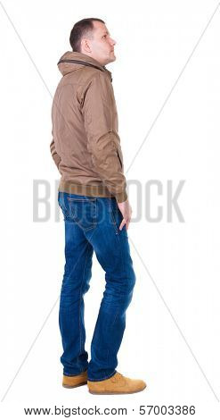 Back view of handsome man in brown windcheater looking up.   Standing young guy in jeans. Rear view people collection.  backside view of person.  Isolated over white background.