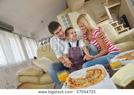 happy young family eating tasty pizza with cheesa and dring healthy and fresh orange juice