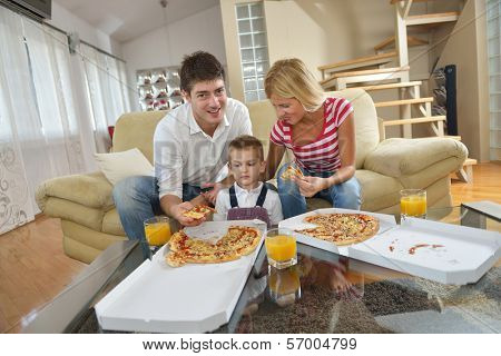 happy young family eating tasty pizza with cheesa and dring healthy and fresh orange juice