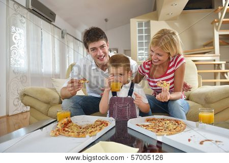 happy young family eating tasty pizza with cheesa and dring healthy and fresh orange juice