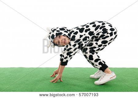 Little boy dressed as cow sitting in the grass