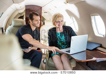 Businessman with female colleague discussing over laptop on private jet