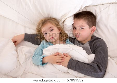Affectionate Young Brother And Sister Lying In Bed