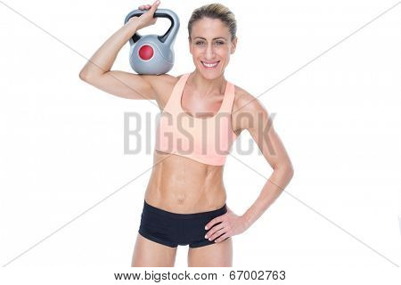 Female blonde crossfitter holding kettlebell smiling at camera on white background