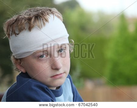 Sad young boy with bandage on his head 
