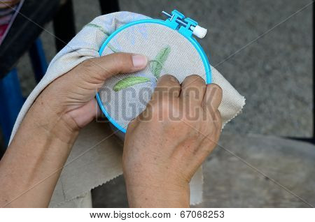 woman hands doing cross-stitch