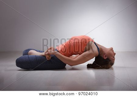 Beautiful sporty fit yogini woman practices yoga asana Matsyasana - fish pose in studio