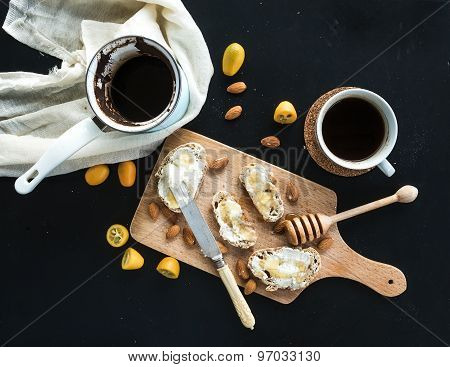 Breakfast set: pot or cezve of coffee, cup, kitchen towel, baguette slices with butter cream, almond