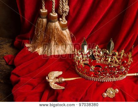 Golden king's crown and scepter on red velvet