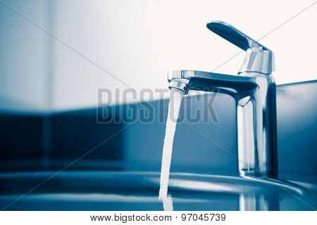 faucet with flowing water, blue tone