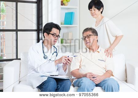 Doctor and patient healthcare concept. Asian elder man consult family doctor, sitting on sofa. Senior retiree indoors living lifestyle.
