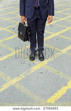 Legs of businessman with briefcase walking down trottoire