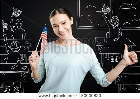 Best holiday of the year. Cheerful professional teahcer holding american flag and conducting lesson while celebrating independence day