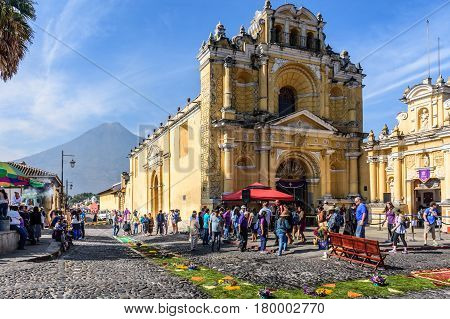 Antigua, Guatemala - April 2 2017: Pine needle procession carpets outside Hermano Pedro church during Lent against backdrop of Agua volcano in colonial town with most famous Holy Week celebrations in Latin America.