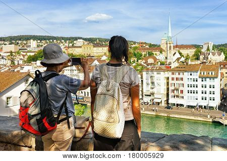 Two Female Tourists Backpackers Looking Taking Photos At Limmatquai Zurich