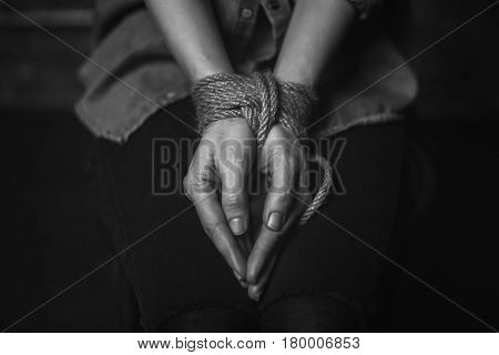 Motionless. Trapped abducted scared girl being imprisoned and sitting in a dark place with her hands tied up