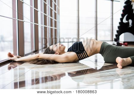 Young Woman Practice Yoga Matsyasana Against Windows In Studio.