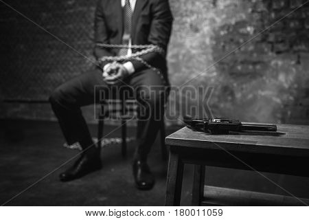 Perfect chance. Smart quick witted businessman coming up with a plan of escape while looking at the gun lying on the table nearby