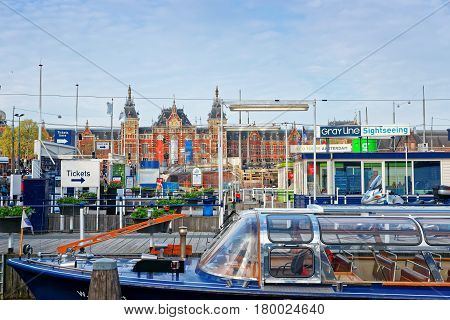Amsterdam Netherlands - May 3 2013: Canal boats on Open Havenfront in Amsterdam Netherlands. Central train station on the background