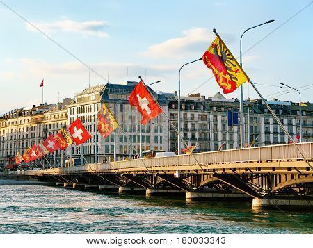 Geneva Lake and Mont-Blanc bridge with flags Geneva city center of Switzerland. People on the background
