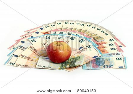 A beautiful ripe fresh apple lies on a pile of European paper currency euro