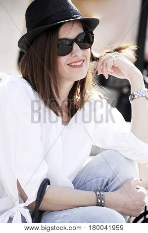 Young and trendy hipster woman in black hat is wriggling her hair. Lifestyle concept.