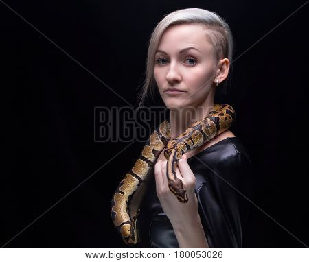 Woman in leather dress with ball python on black background
