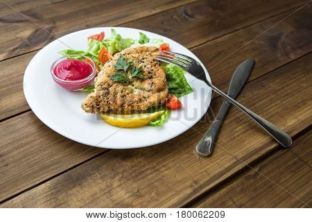served Homemade Breaded Schnitzel with salad and berry sauce on old wooden table