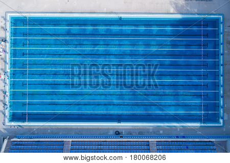 Top view bird eye view of swimming pool with marked lanes and starting platform.