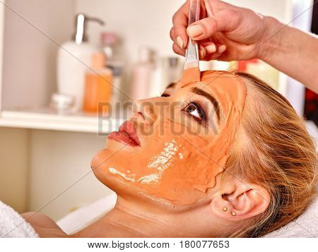 Collagen face mask . Facial skin treatment. Woman receiving cosmetic procedure in beauty salon. Bottle with moisturizing cream on background.